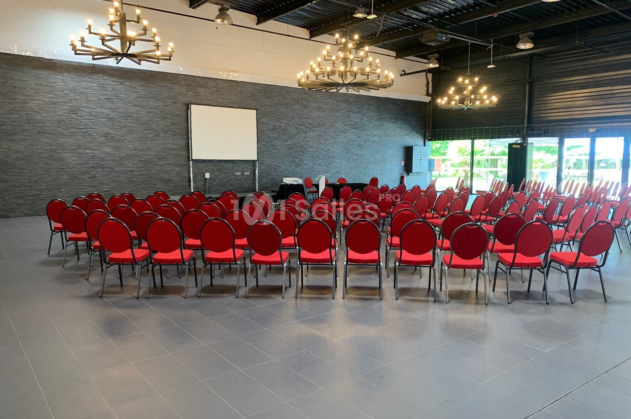 Salle de conférence avec des chaises rouges disposées en cercle autour d'un écran de projection.