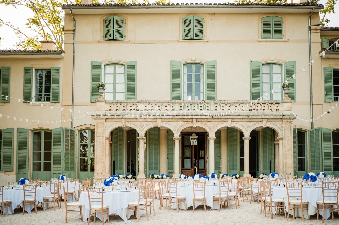 Façade d'un bâtiment ancien avec tables et chaises disposées en extérieur pour un événement.