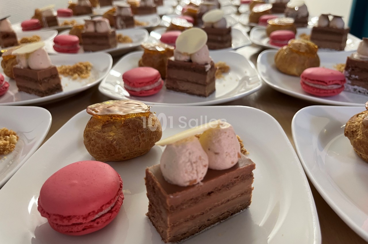 Assortiment de desserts individuels comprenant macarons, choux et gâteaux au chocolat sur des assiettes blanches.