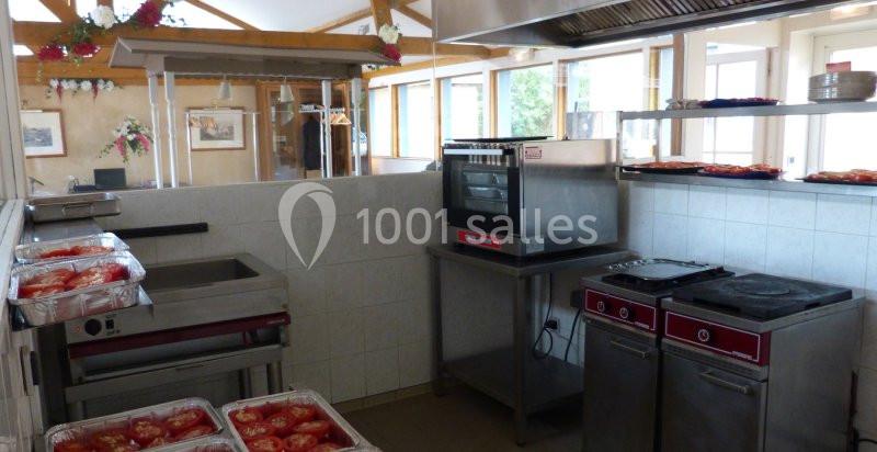 Cuisine professionnelle équipée avec four, plaques de cuisson, plans de travail et plats de tomates préparées.