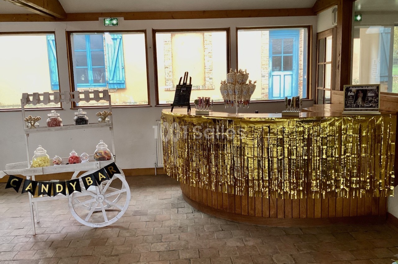 Chariot et comptoir décorés avec des friandises, guirlandes dorées et lumière naturelle dans une salle lumineuse.