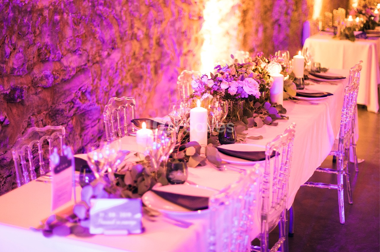 Table décorée avec élégance, ornée de fleurs, bougies et vaisselle raffinée, dans une ambiance lumineuse tamisée.