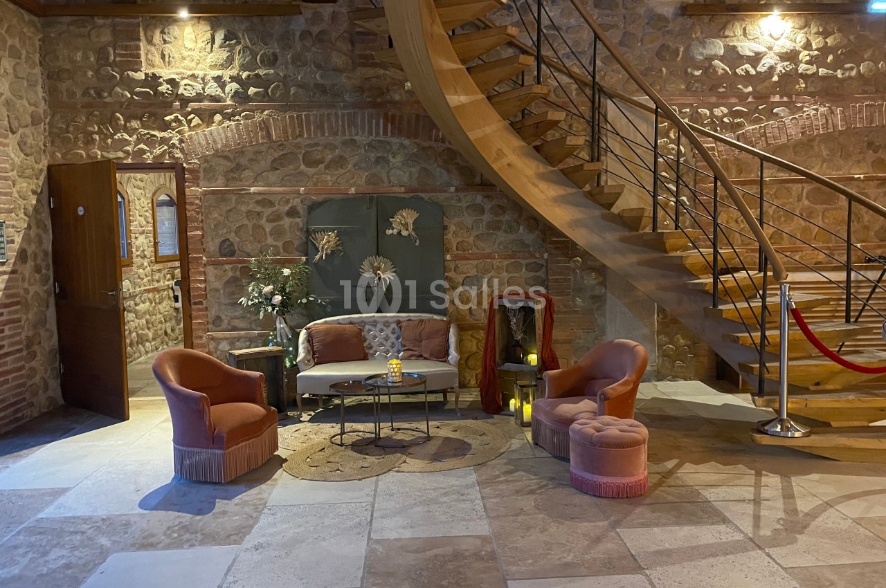 Espace cosy avec fauteuils, table basse et décoration florale, situé au pied d'un escalier en bois dans un intérieur en…