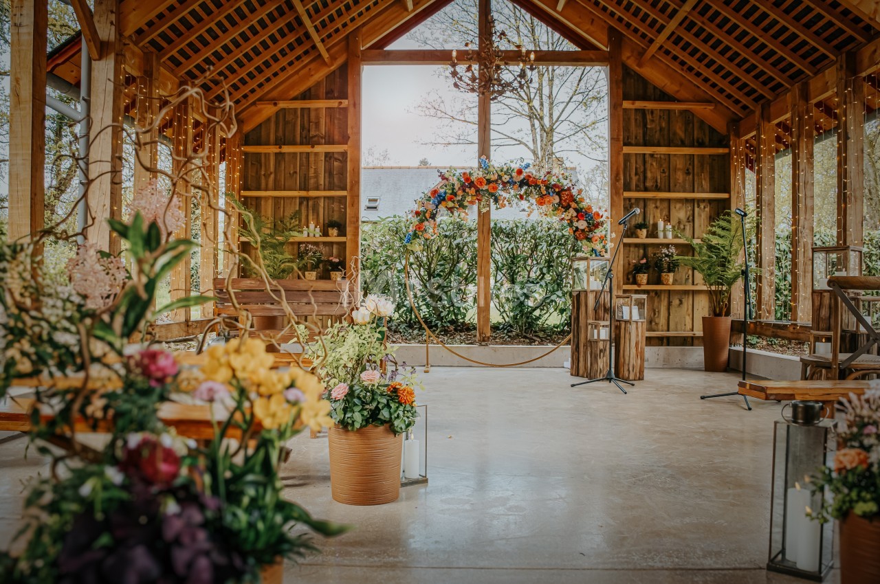 Salle en bois décorée pour un mariage, avec des fleurs colorées, un arche floral et des lanternes.