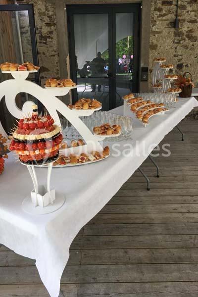 Table de buffet avec verrines, petits fours et une pièce montée, disposée sur une nappe blanche en extérieur.