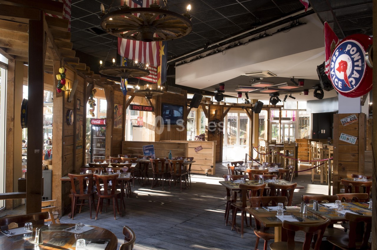 Salle de restaurant au décor rustique avec tables en bois, drapeaux suspendus et éclairage chaleureux.