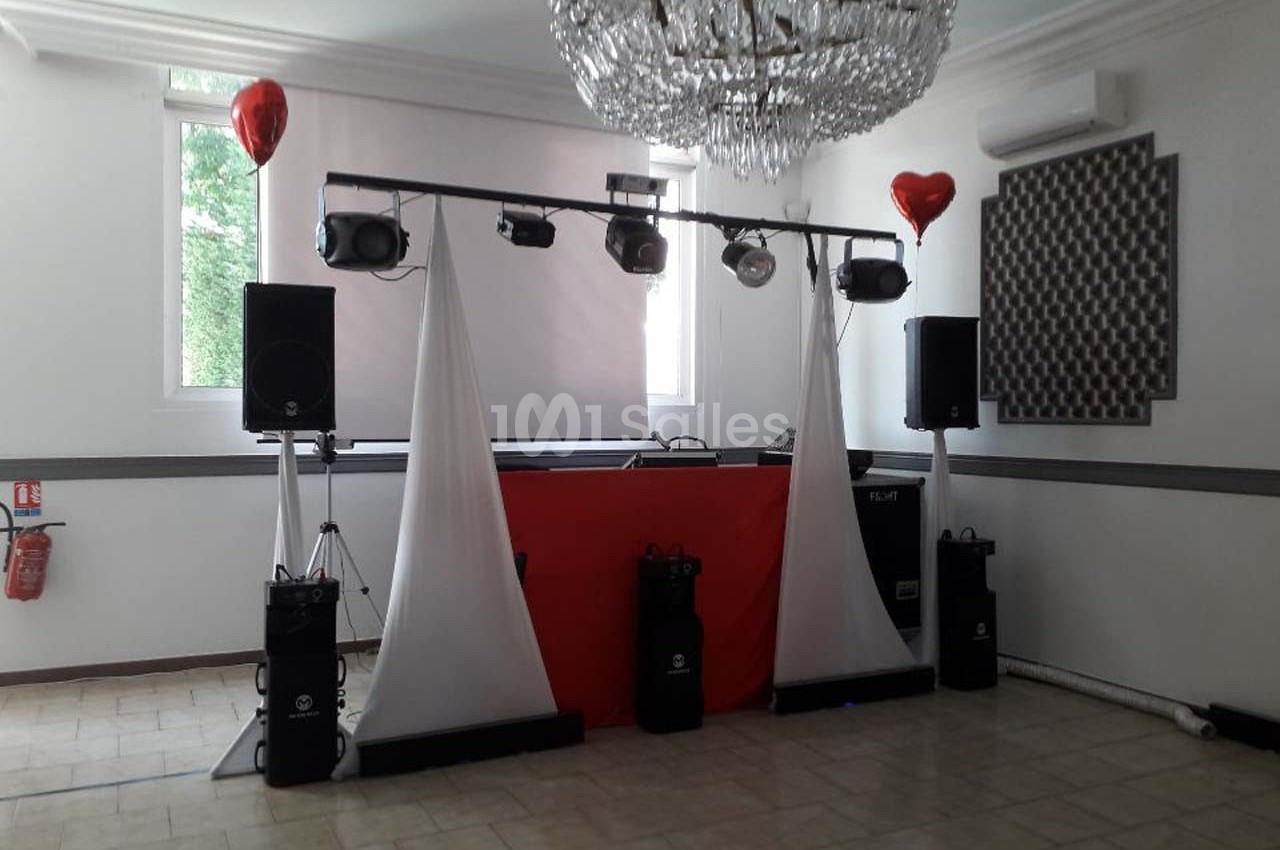 Installation de matériel de sonorisation et éclairage dans une salle avec un lustre et des ballons rouges en décoration.