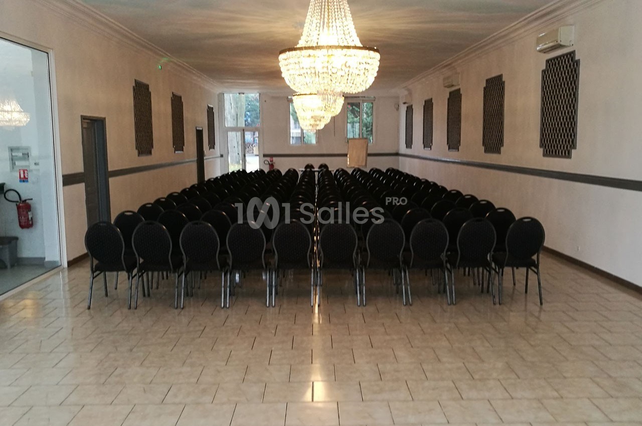 Salle de réception avec rangées de chaises noires alignées sous des lustres en cristal, sol carrelé clair.