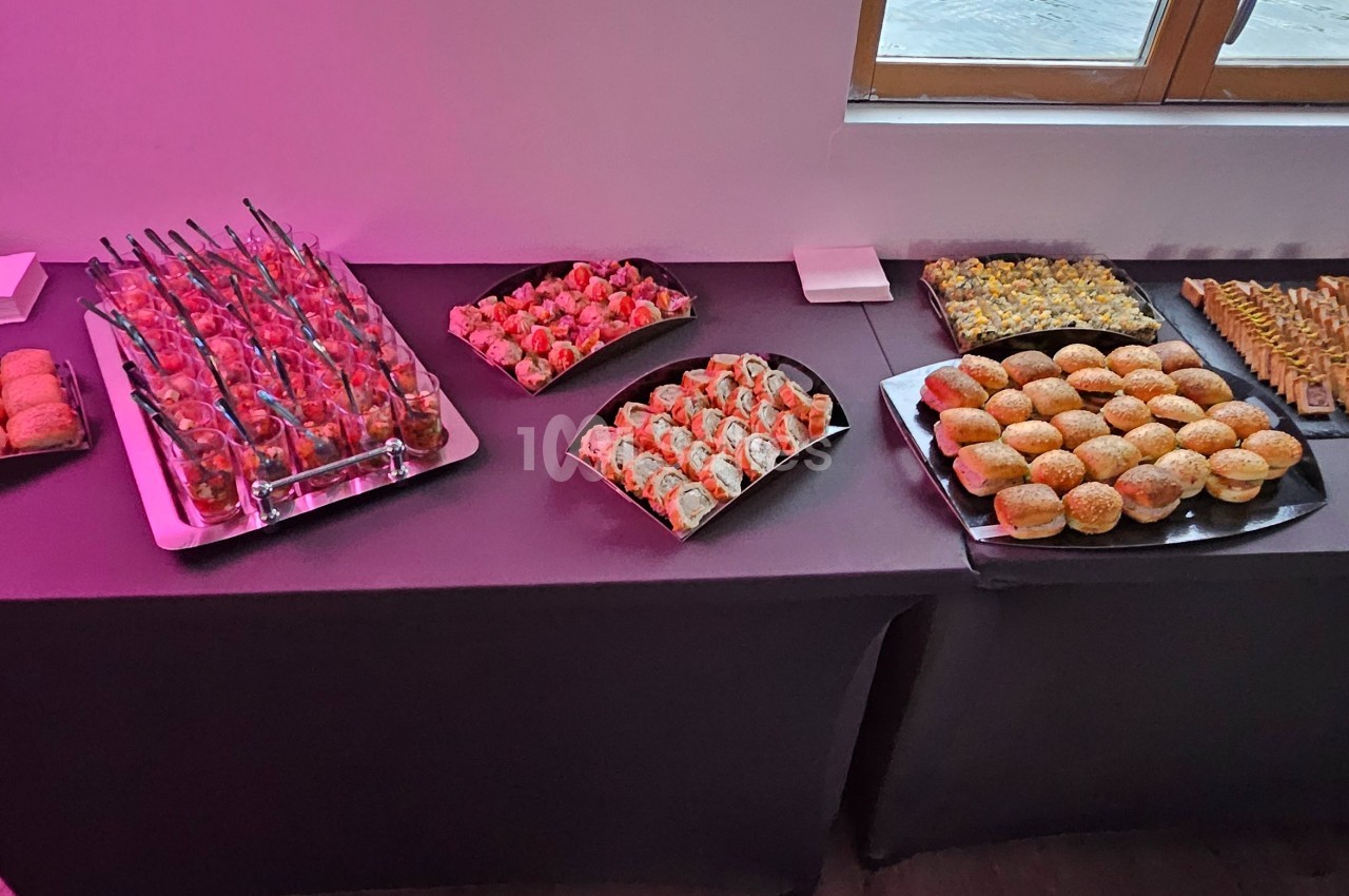 Buffet de petits fours variés disposés sur une table noire, avec des fenêtres en arrière-plan.
