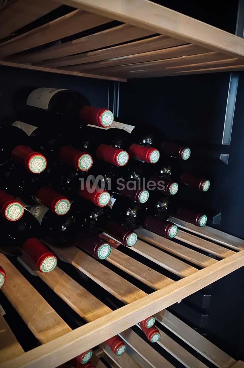 Bouteilles de vin rouge disposées horizontalement sur des étagères en bois dans une cave à vin.