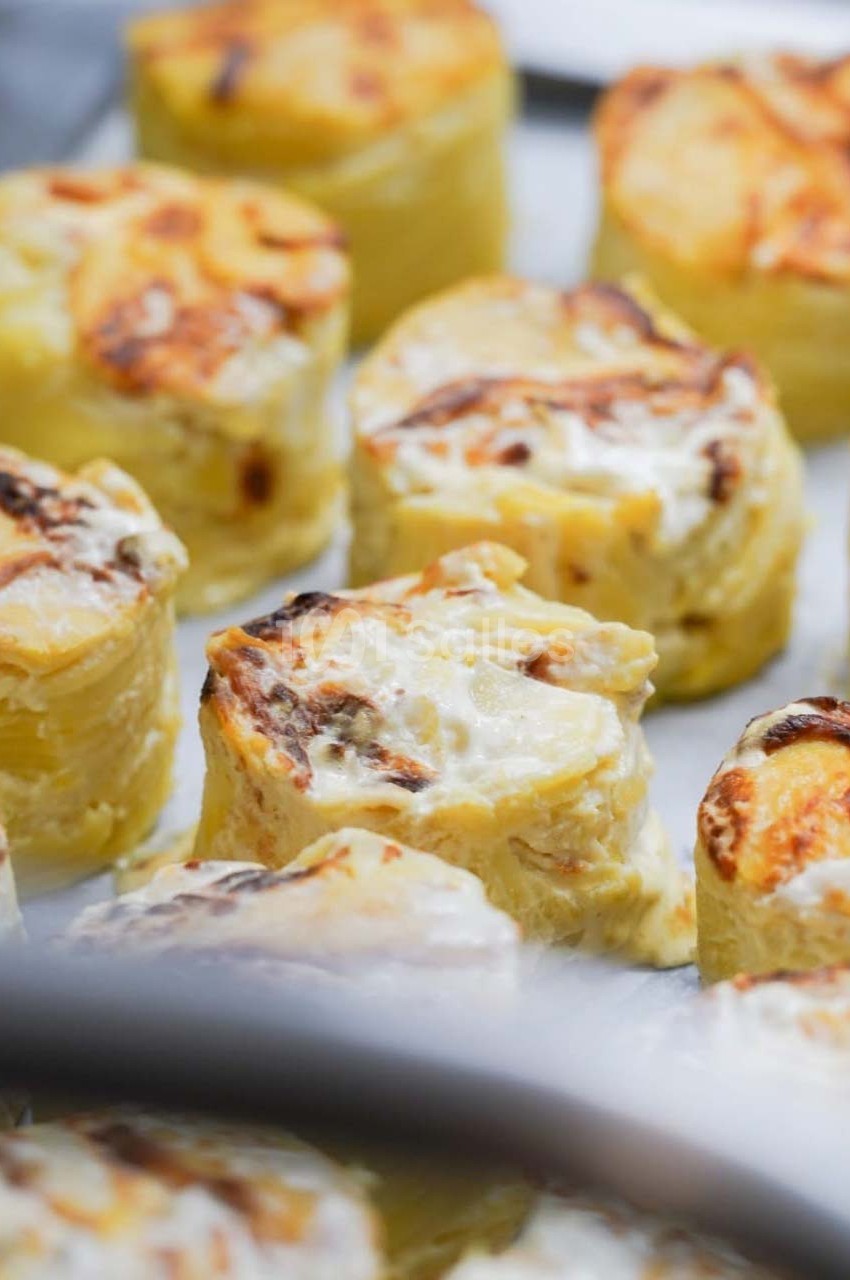 Pommes de terre gratinées en portions individuelles, dorées et crémeuses, disposées sur une plaque de cuisson.