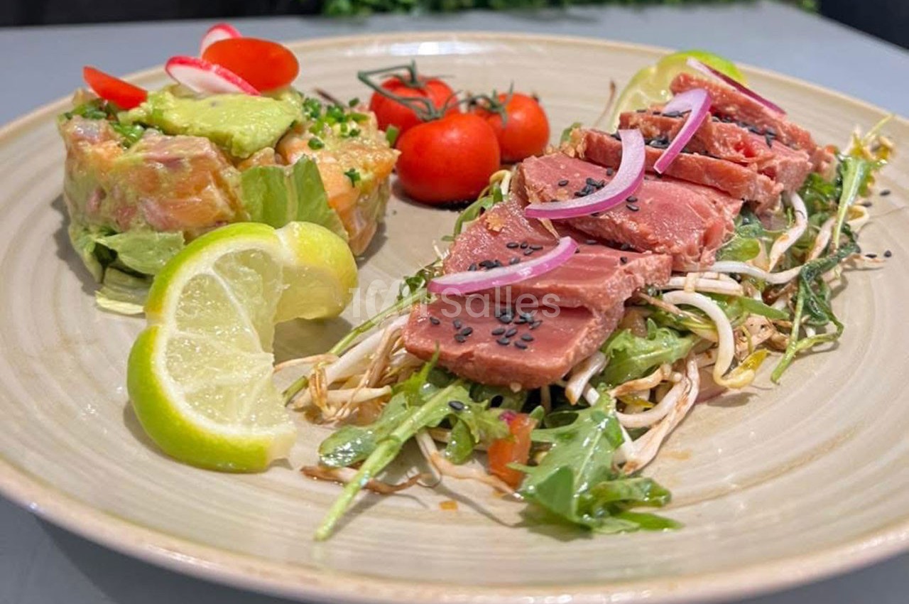 Assiette composée de thon mi-cuit sur lit de roquette, tartare de saumon à l'avocat, tomates cerises et quartiers de citron.