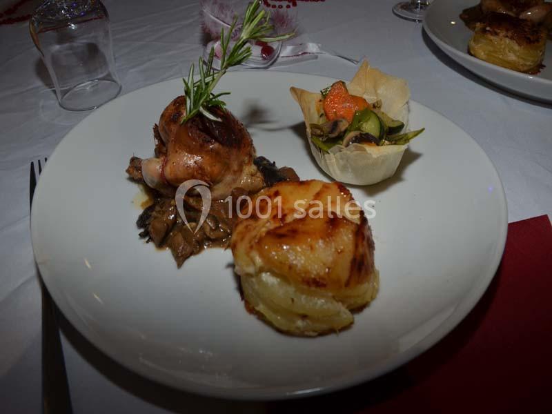 Assiette composée d'une cuisse de volaille sur lit de champignons, gratin de pommes de terre et garniture de légumes.