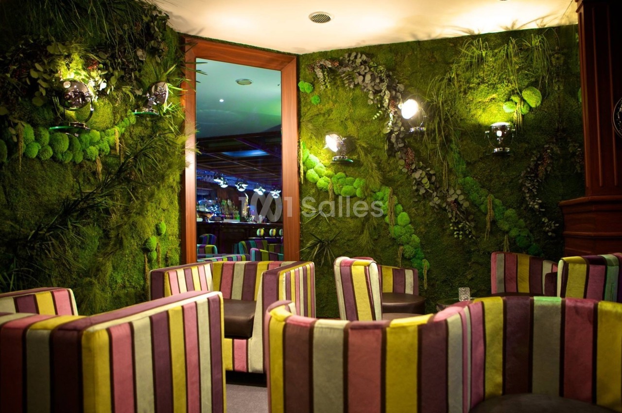 Salle avec des fauteuils rayés colorés, murs recouverts de végétation et éclairage tamisé.