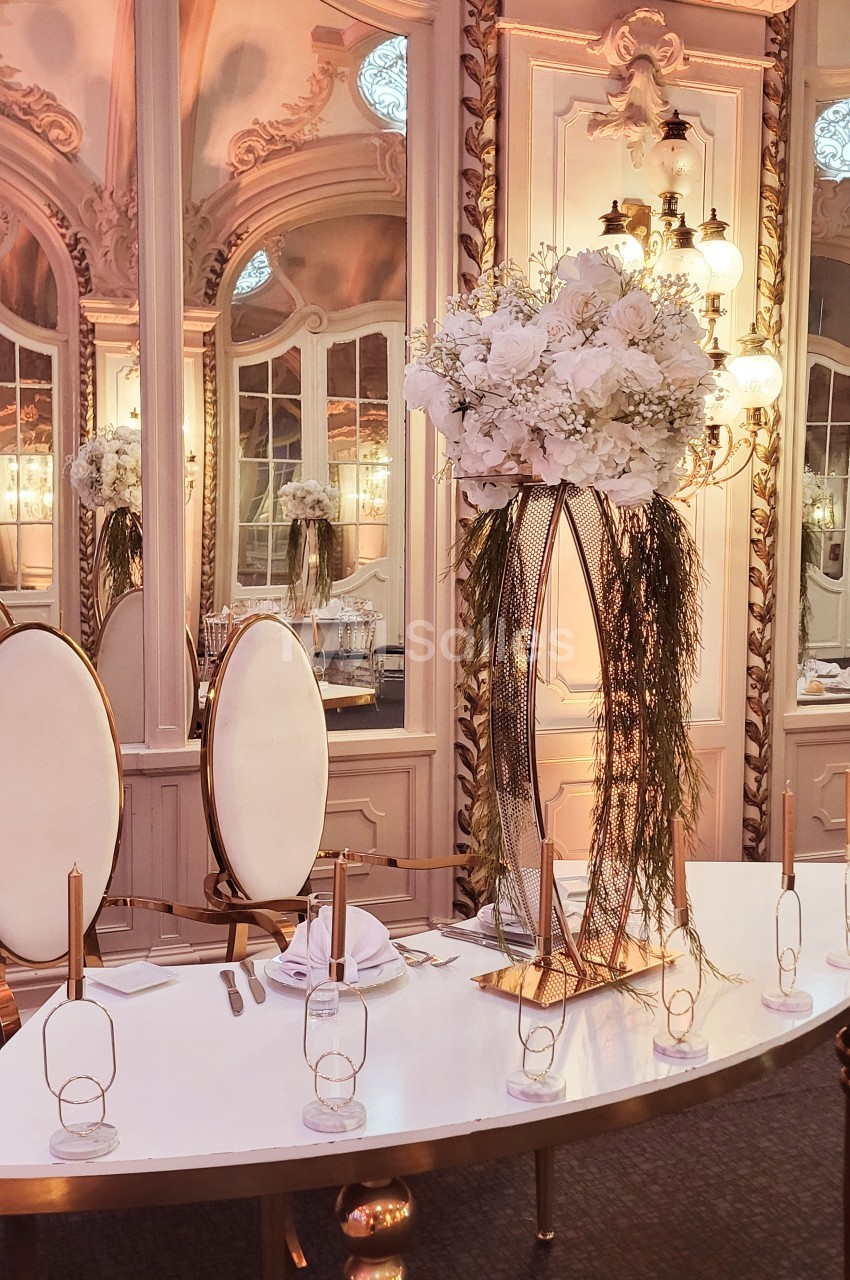 Table élégante décorée de fleurs blanches et de bougies dorées dans une salle au style classique avec miroirs ornés.