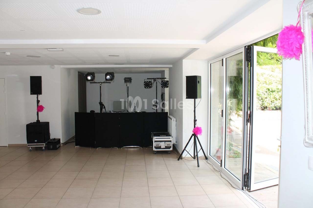 Salle lumineuse avec équipement de sonorisation et éclairage installé près de grandes portes vitrées ouvertes.