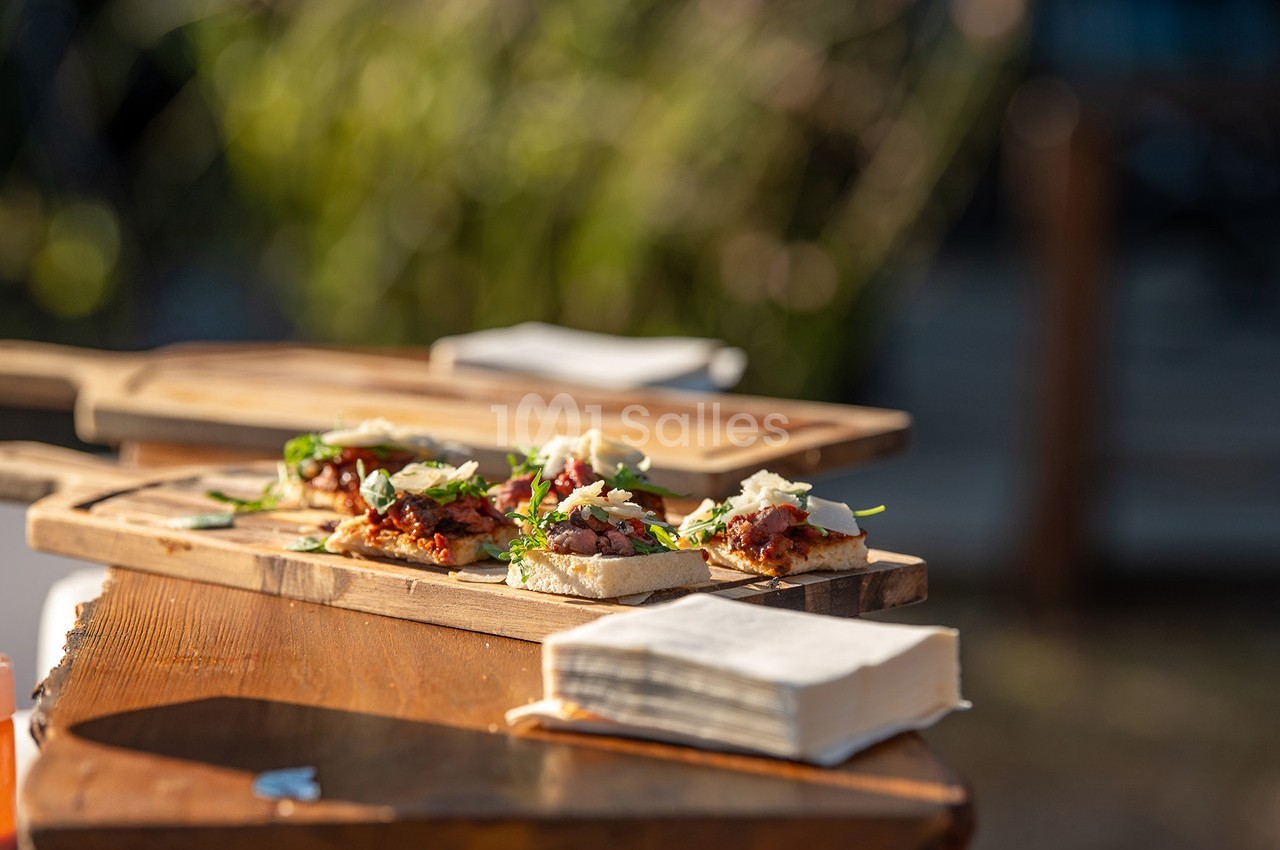 Tranches de pain garnies de légumes, fromage et herbes, présentées sur une planche en bois en extérieur.