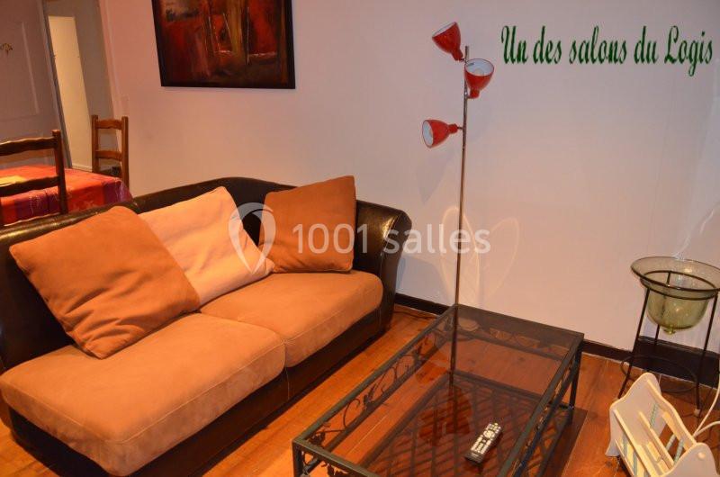 Canapé brun avec coussins, table basse en verre, lampe rouge et décoration intérieure dans un salon chaleureux.