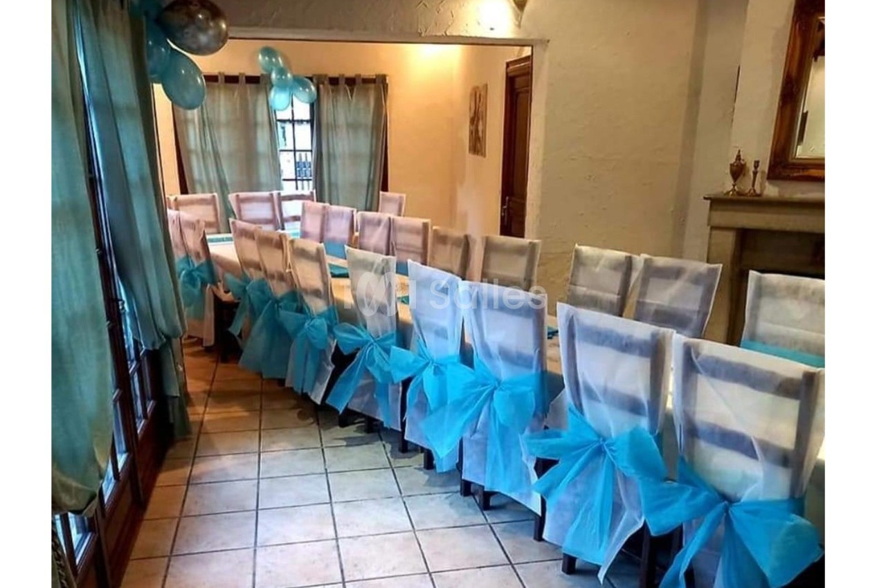 Chaises alignées dans une salle décorée avec des nœuds en tissu bleu et des ballons pour un événement festif.