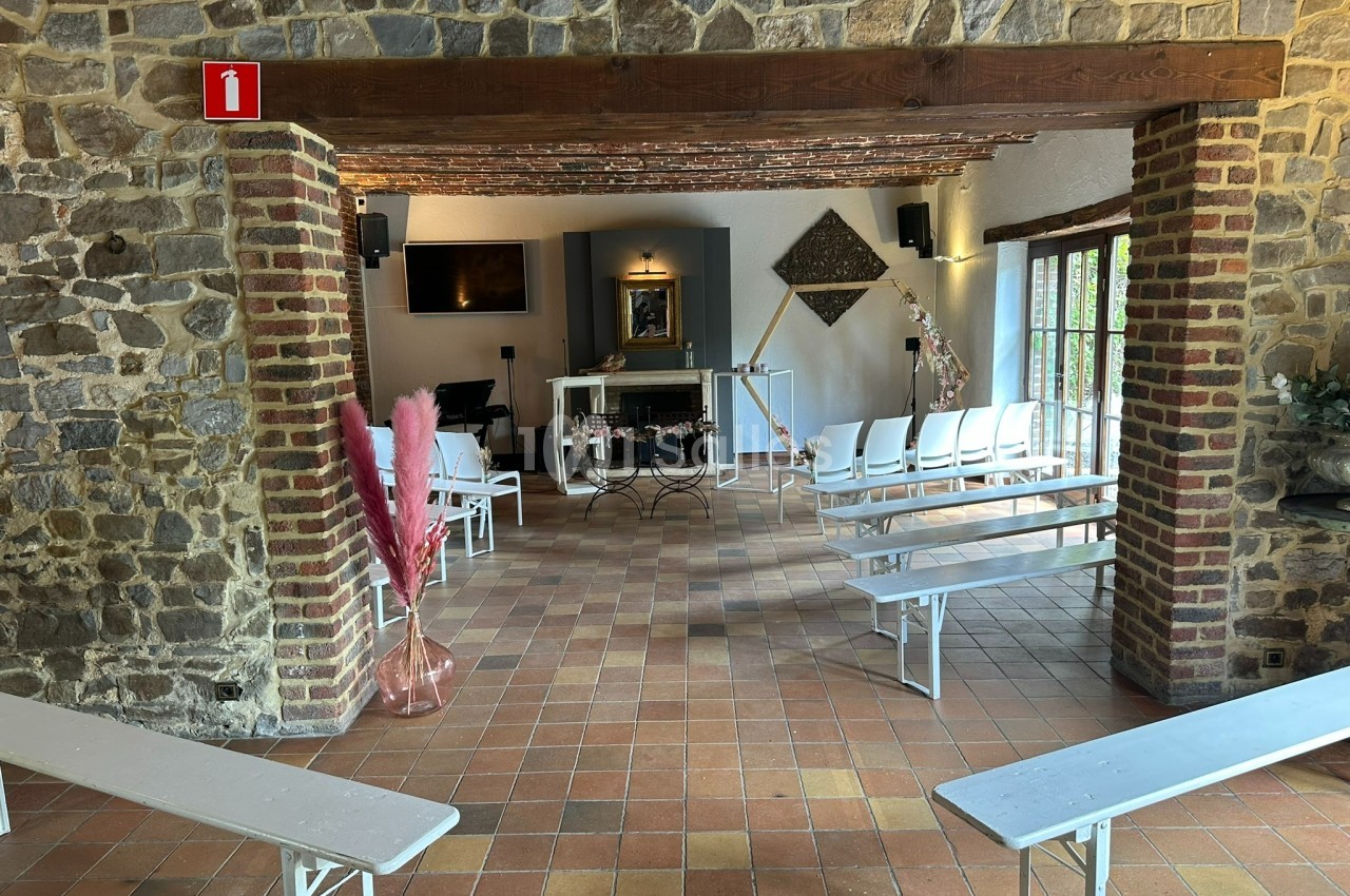 Salle avec des bancs blancs, murs en pierre et briques, décorations simples, éclairage naturel et vue sur un autel.