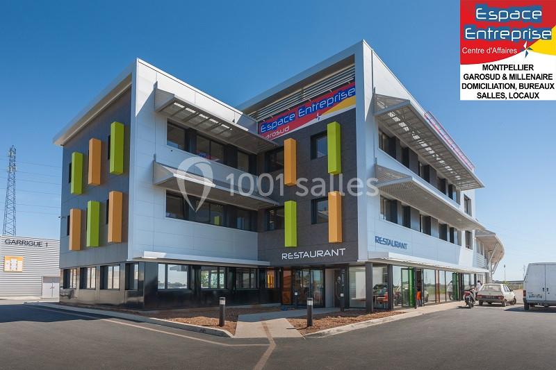Bâtiment moderne à trois étages avec enseignes ’Espace Entreprise’ et ’Restaurant’, situé sur un parking dégagé.