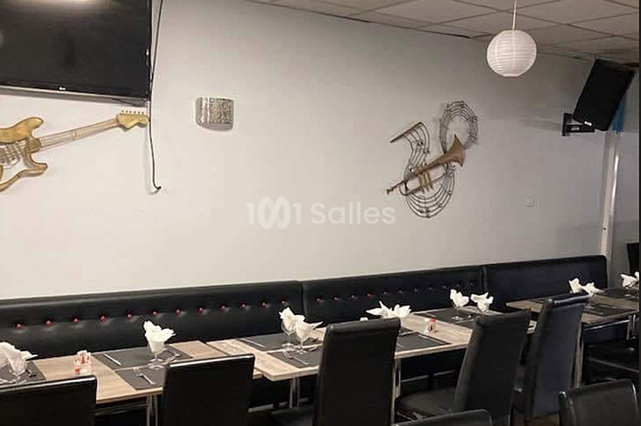 Salle de restaurant avec tables dressées, chaises noires et décorations murales en forme de guitares.