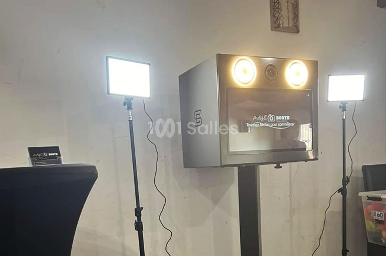 Borne photo avec éclairages LED sur trépieds, installée dans une pièce au mur clair et décor minimaliste.