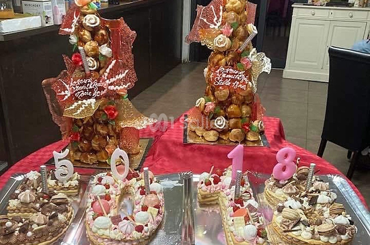 Desserts variés, dont des chiffres en pâtisserie et des pièces montées, présentés sur une table rouge.