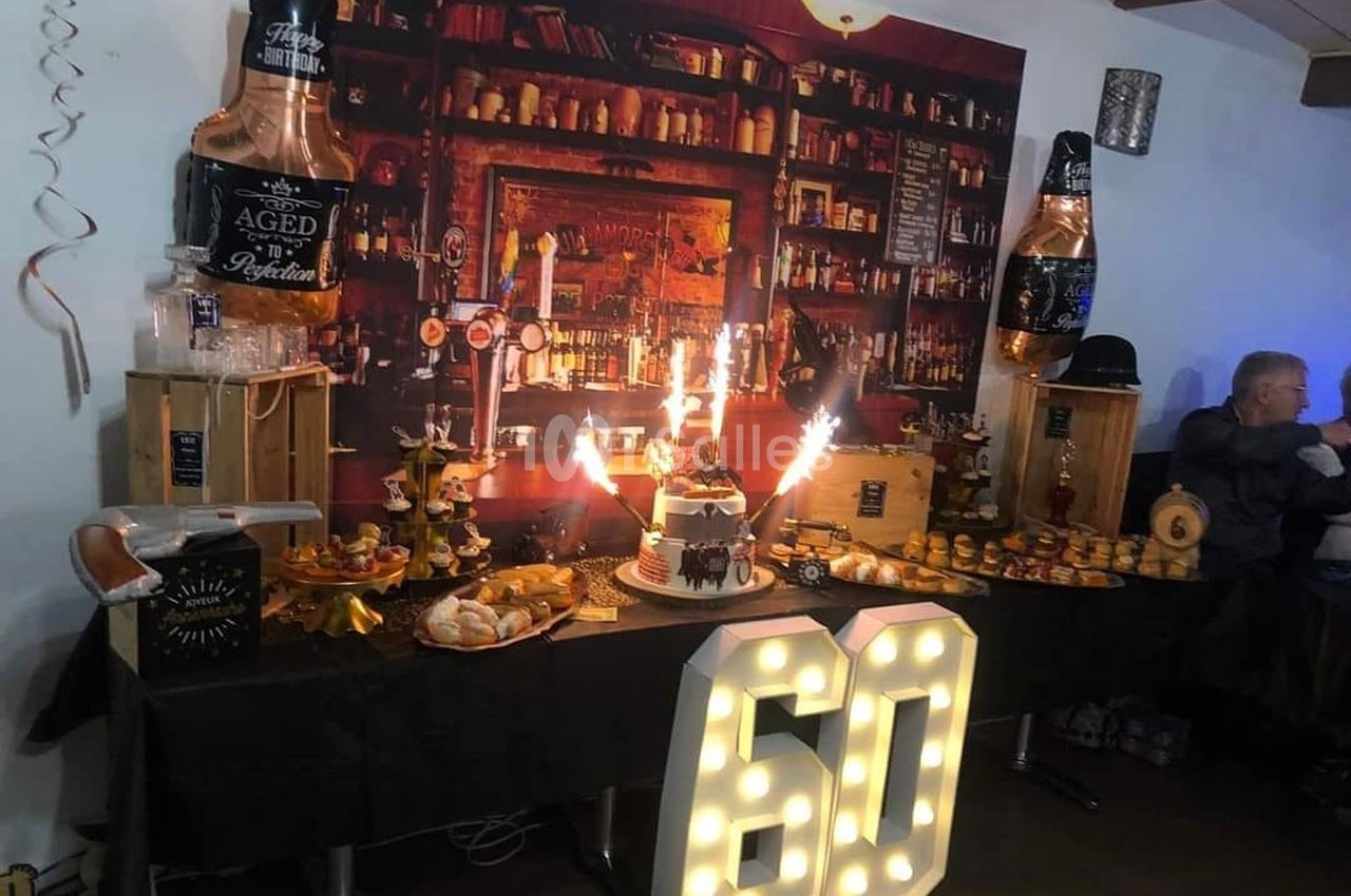Table décorée pour un 60e anniversaire avec gâteau, bougies étincelantes, nourriture et décorations sur le thème d'un bar.