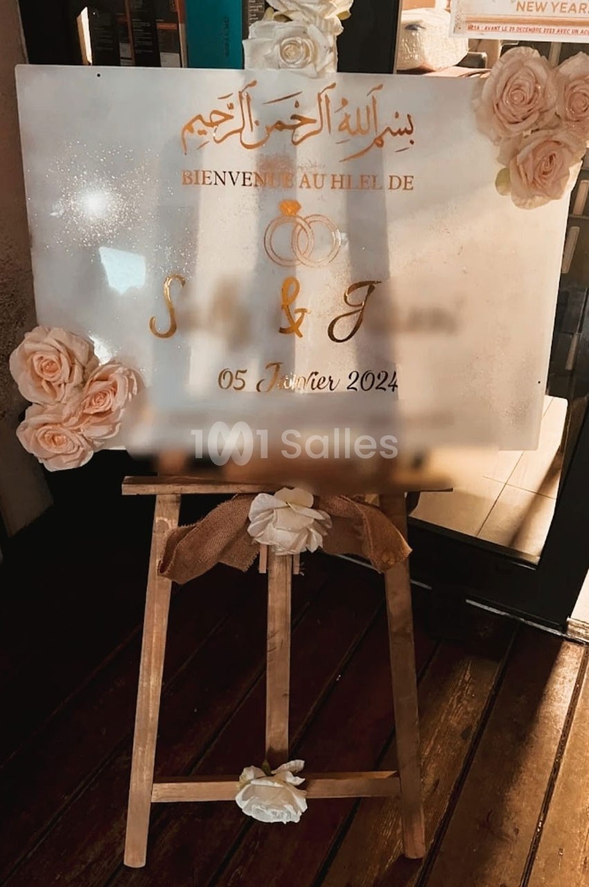 Panneau de bienvenue pour un mariage, décoré de roses et posé sur un chevalet en bois.