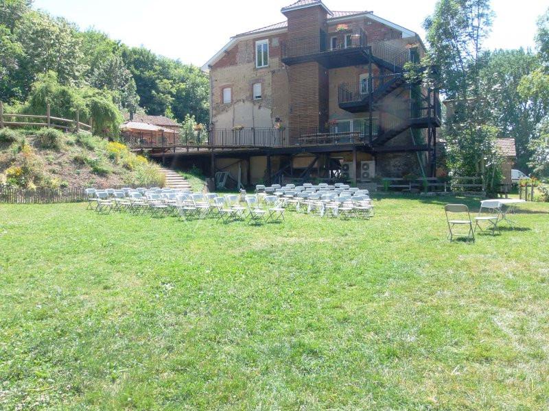 Chaises disposées en rangées sur une pelouse devant un bâtiment en briques avec un escalier extérieur.