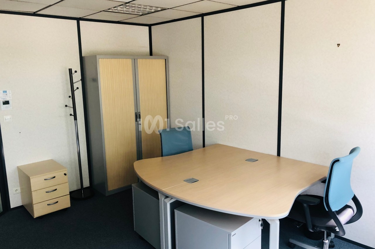 Bureau lumineux avec deux chaises, un bureau d'angle, une armoire en bois clair et un porte-manteau dans un espace fermé.