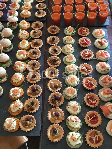 Plateau de canapés variés avec verrines de soupe rouge, disposés sur une table pour un buffet ou un événement.