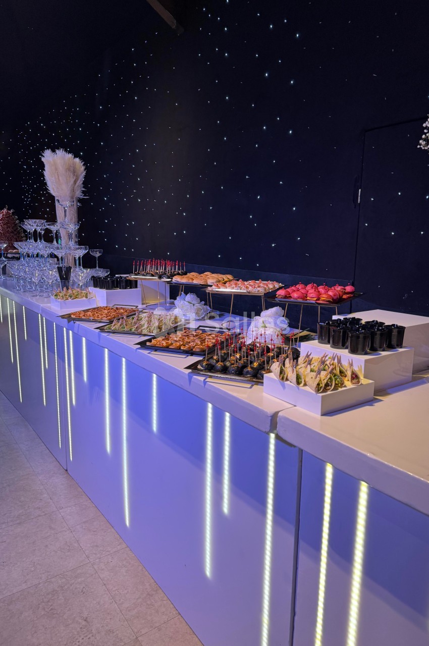 Buffet élégant avec une variété de plats et amuse-bouches disposés sur une table lumineuse dans un décor étoilé.