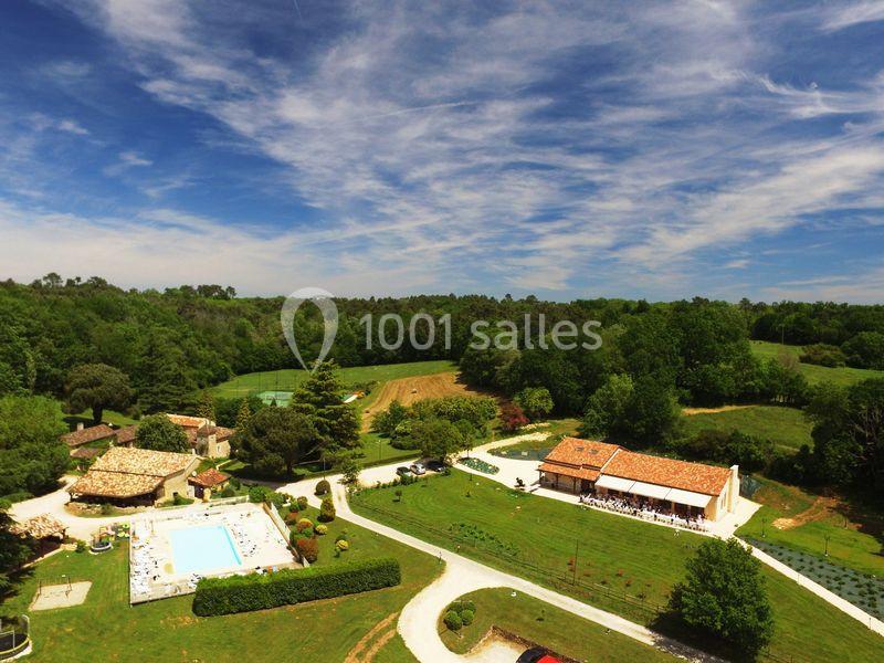 Vue aérienne d'une propriété rurale avec piscine, bâtiments en pierre et espaces verts entourés de forêt.