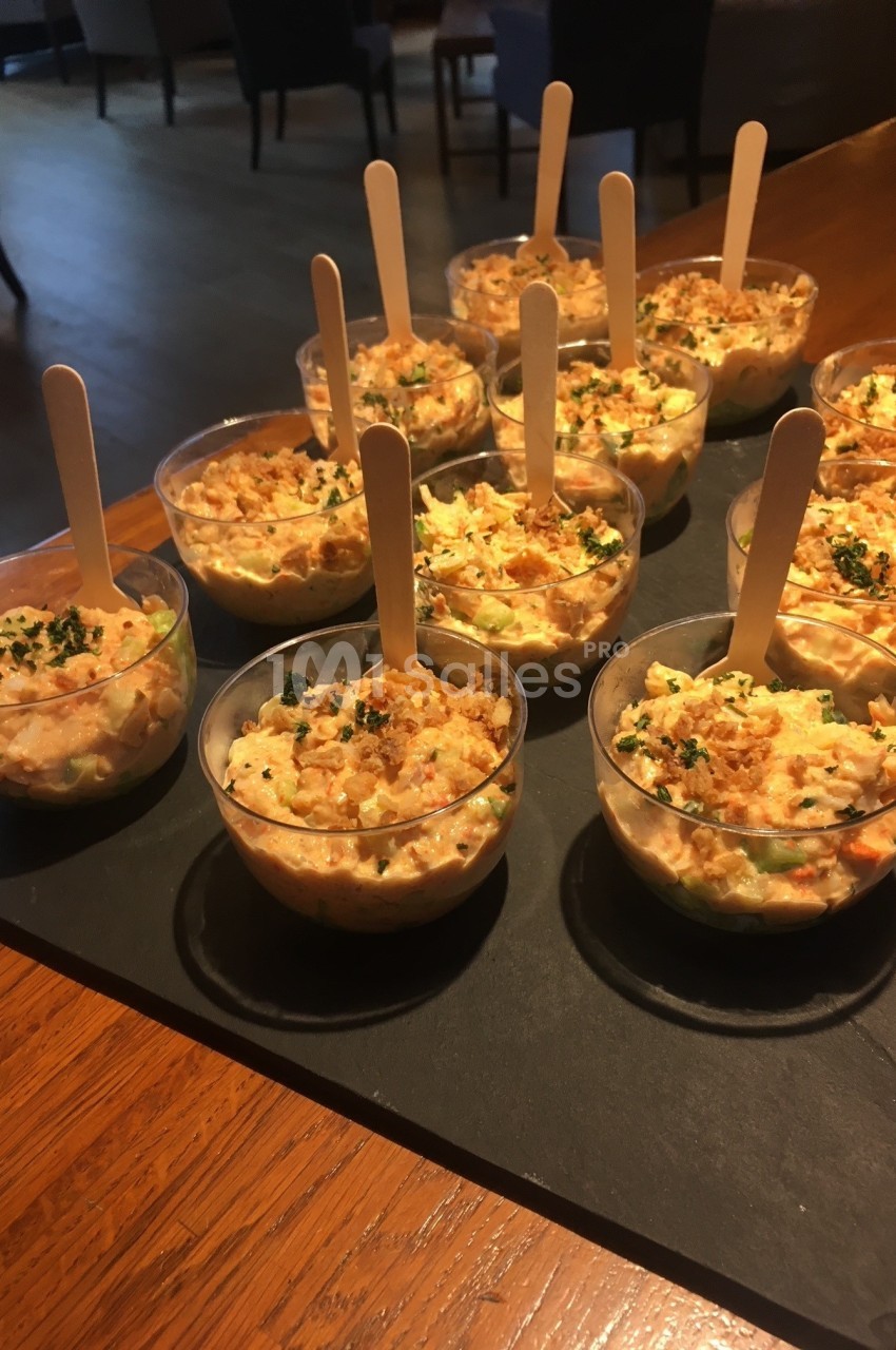 Verrines individuelles de salade crémeuse garnies de persil, servies avec des bâtonnets en bois sur un plateau.