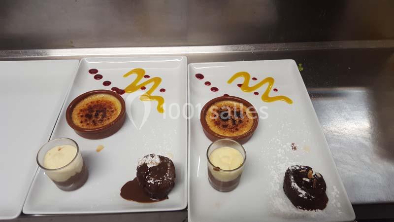 Deux assiettes contenant une crème brûlée, un moelleux au chocolat, une verrine de crème et des décorations de coulis.