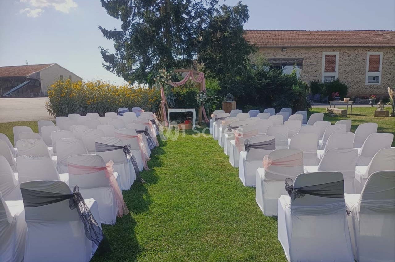 Chaises blanches décorées en rangées face à une arche ornée de tissu rose, installées sur une pelouse en extérieur.