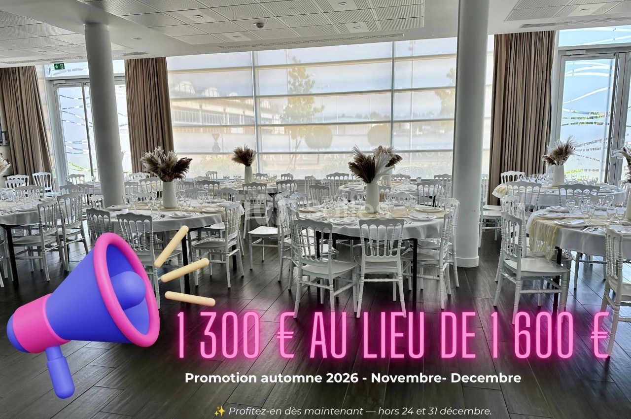 Salle de réception dressée avec tables blanches, chaises Chiavari blanches et centres de table floraux, baies vitrées panoramiques.
