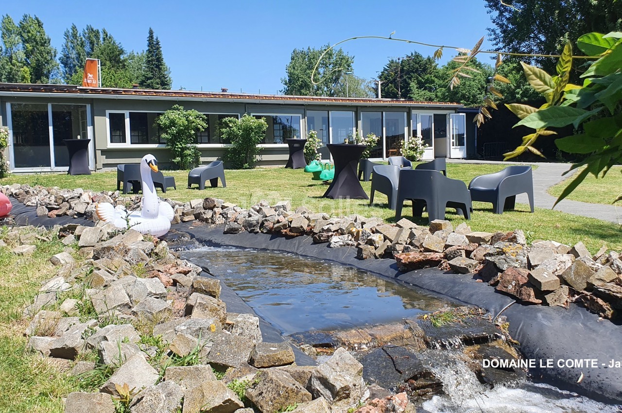 Petit ruisseau bordé de pierres dans un jardin avec des chaises, des tables et des décorations gonflables.