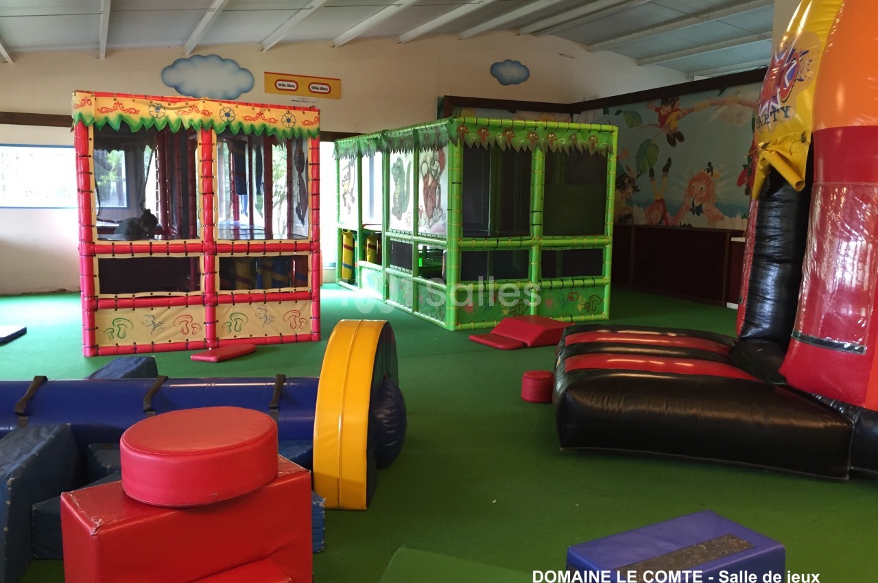 Salle de jeux intérieure avec structures gonflables colorées, modules en mousse et espaces de jeu pour enfants.
