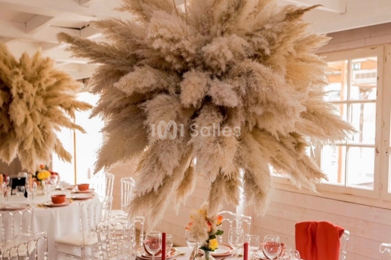 Suspension décorative en herbes de la pampa au-dessus d'une table dressée dans une salle lumineuse.