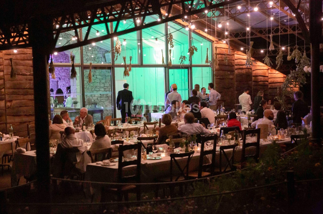 Dîner en soirée dans un restaurant avec des tables dressées, des convives et un éclairage chaleureux sous une verrière.