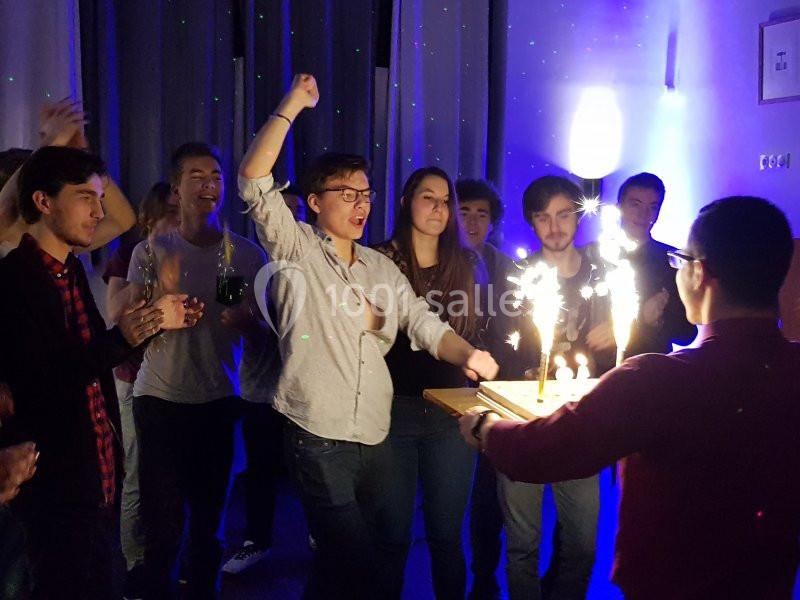 Un groupe de personnes célèbre un anniversaire, avec un gâteau décoré de bougies étincelantes.