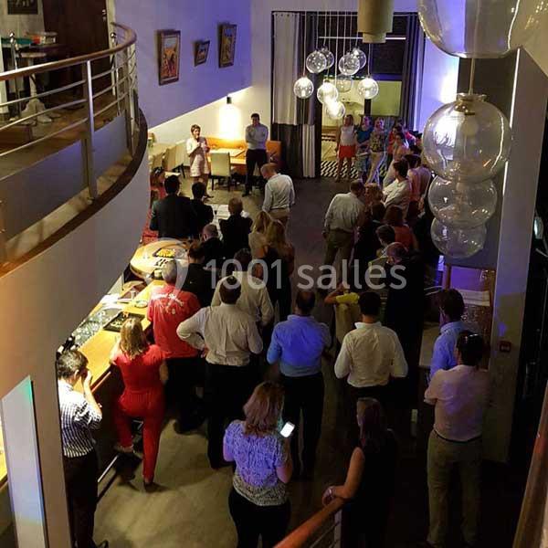 Groupe de personnes réunies dans un espace intérieur moderne, éclairé par des suspensions lumineuses.