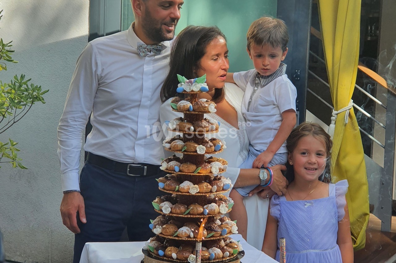 Une famille réunie autour d'une pièce montée et de gâteaux lors d'une célébration en extérieur.