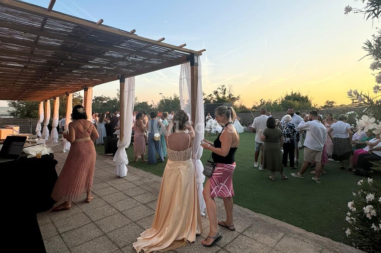 Groupe de personnes rassemblées en extérieur au coucher du soleil, sous une pergola et sur une terrasse.