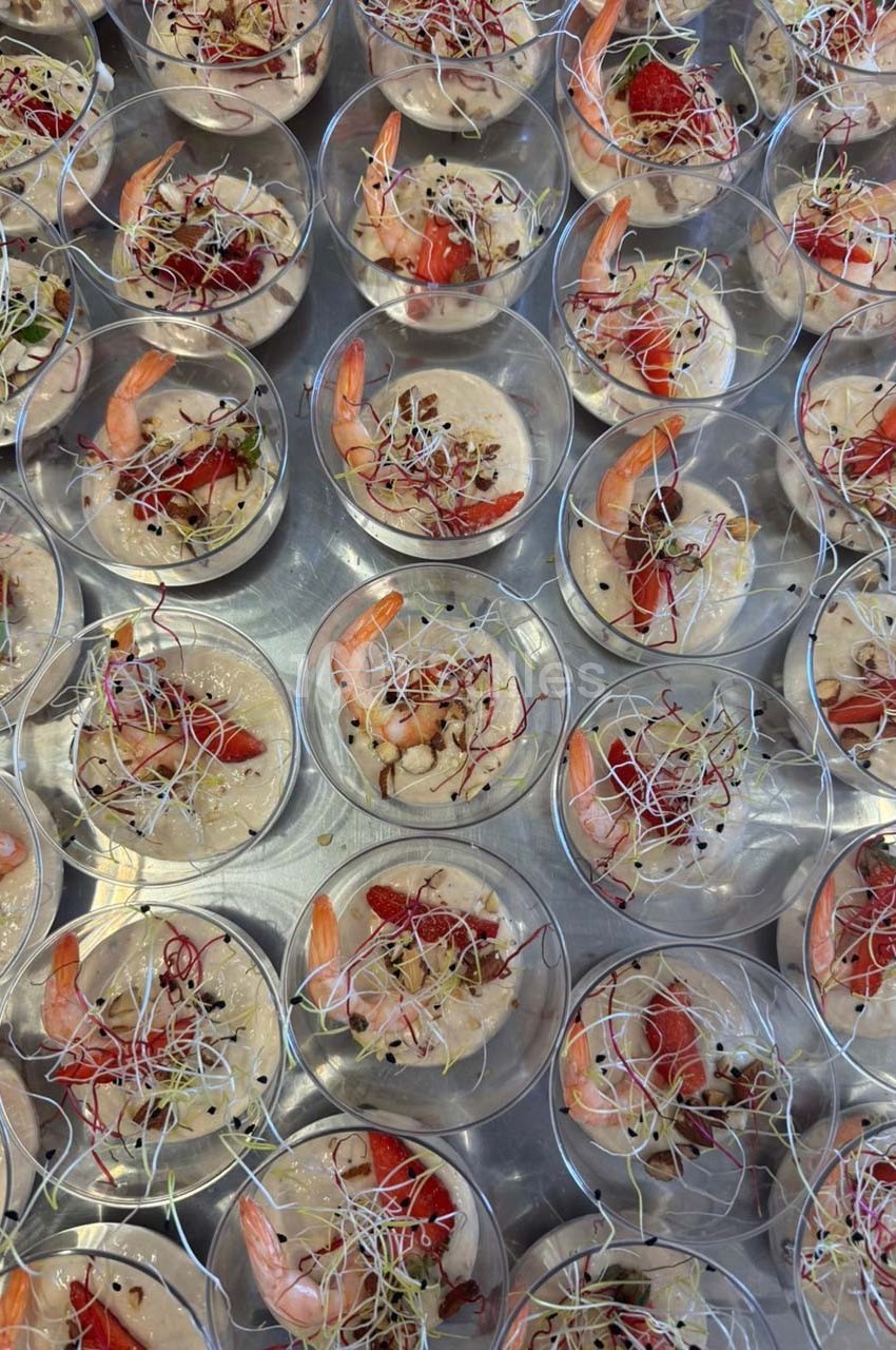 Verrines garnies de crevettes, fraises, pousses germées et éclats de noix, disposées sur un plateau argenté.