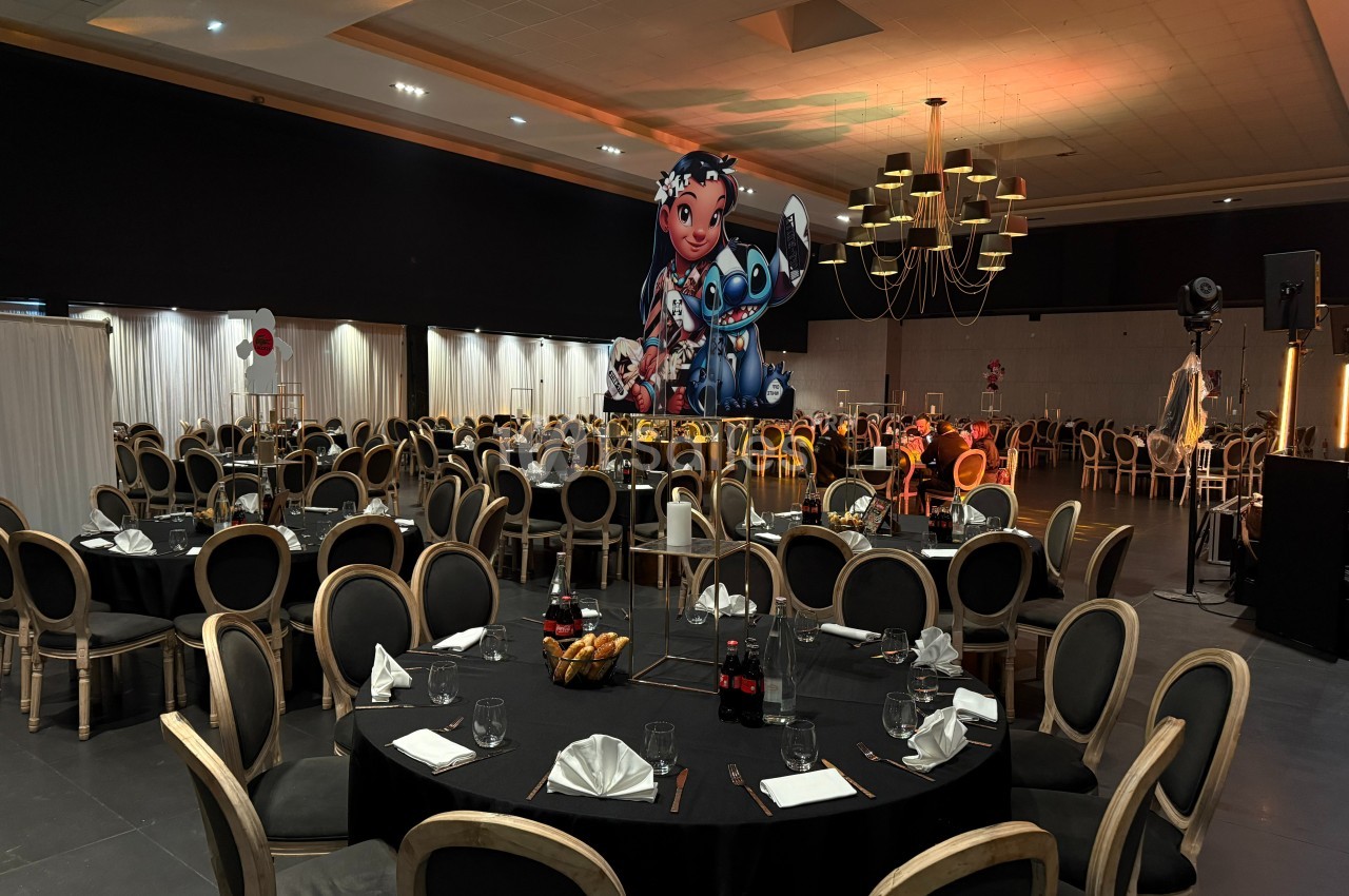 Salle de réception décorée avec des tables rondes dressées et une grande figurine colorée en arrière-plan.
