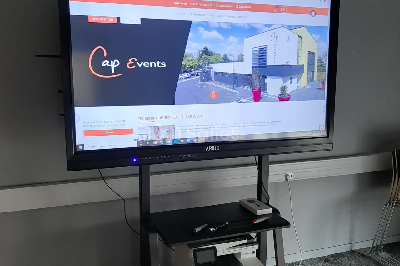 Écran interactif affichant le site web d'une salle événementielle, posé sur un support avec une imprimante en dessous.